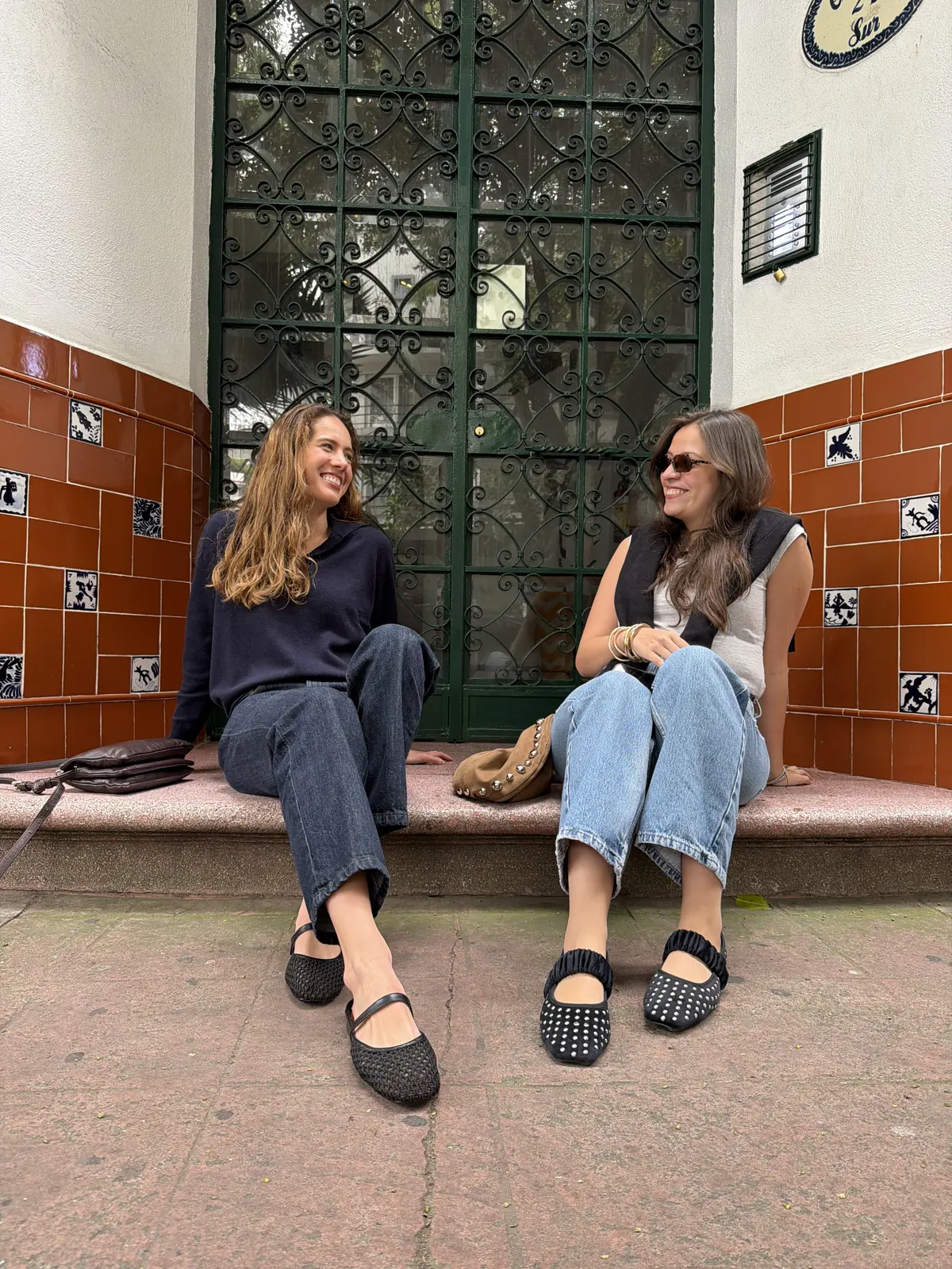 Dos amigas sentadas en una entrada con flats Backless y Margot