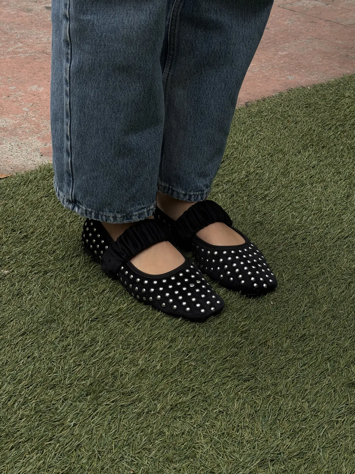 Flats Margot negros con estoperoles sobre el pasto